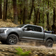 A photo of the Ford F-150 Lightning electric truck driving on a trail.